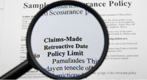 A magnifying glass examining an E&O insurance policy to highlight key terms like "Claims-Made" and "Retroactive Date."